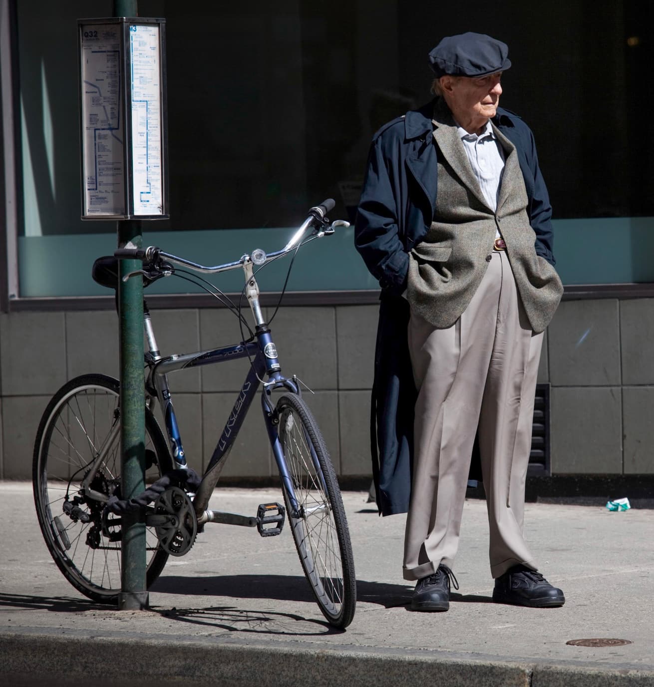 An older man standing beside a bicycle on a New York sidewalk